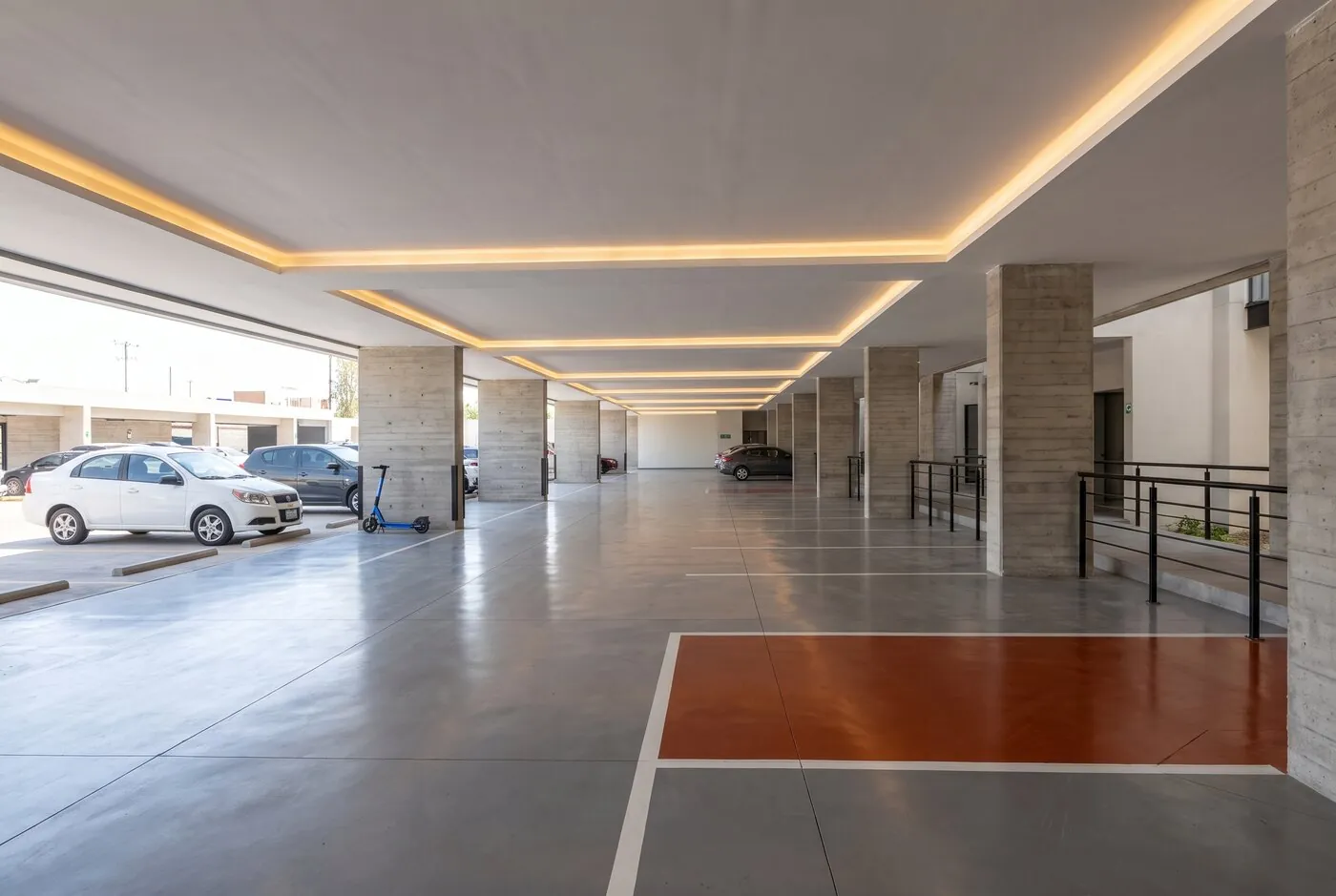 Estacionamiento techado en planta baja con plafón iluminado y cajones marcados
